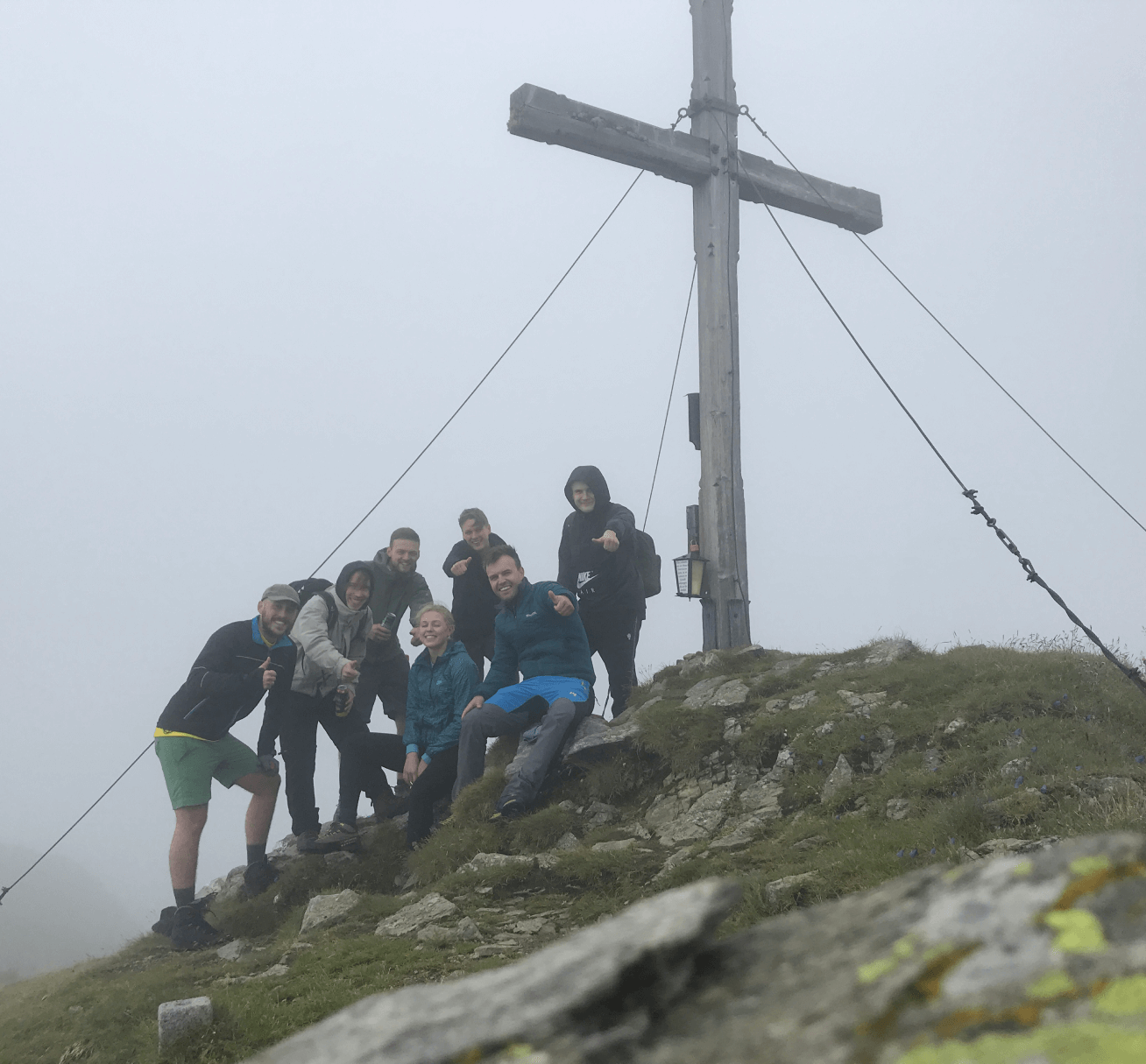 team photo at the peak of a mountain close to the summit cross in the mist
